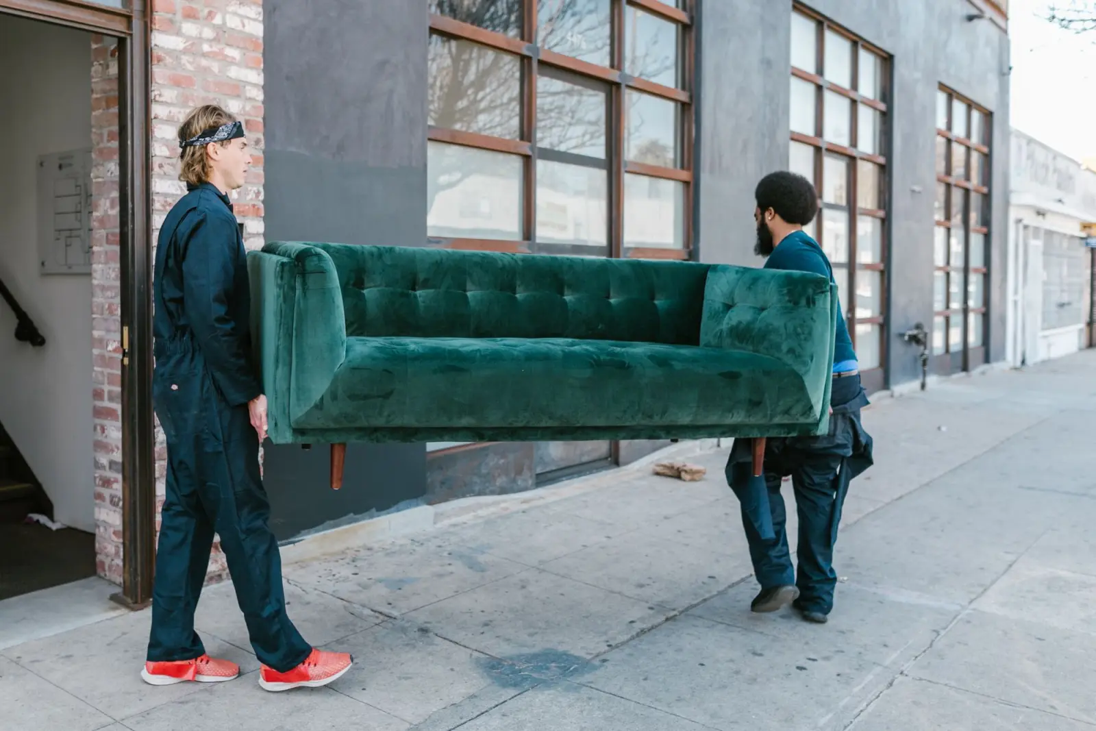 Two movers carrying a sofa out to a delivery truck