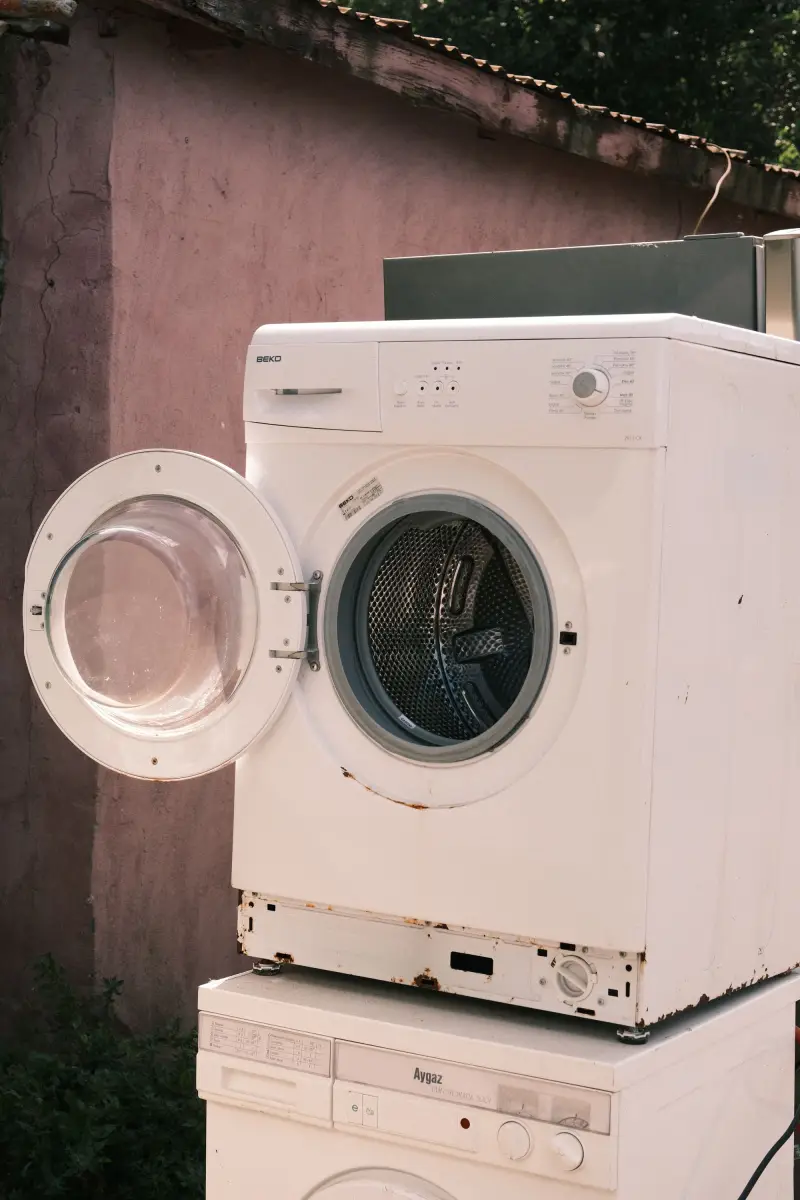 Old stacked washer and dryer set outside for removal