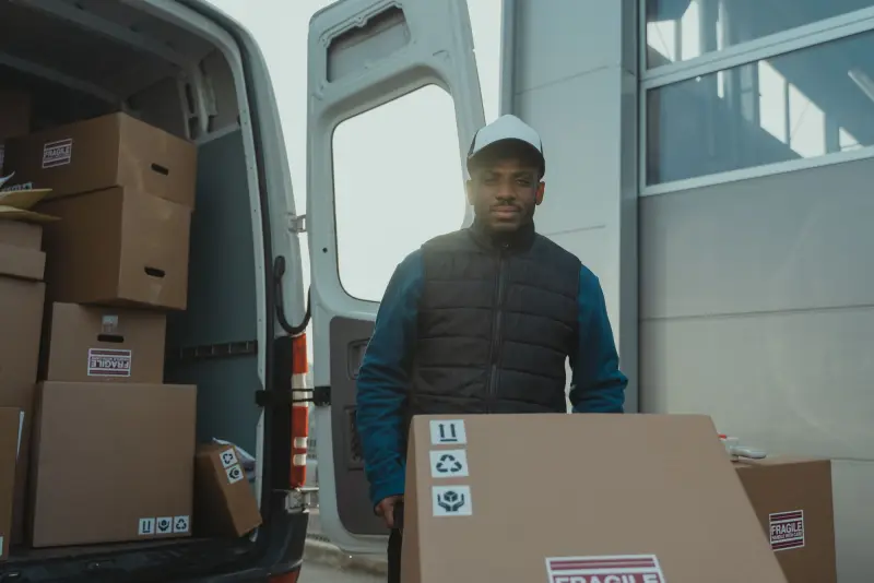 Delivery worker unloading boxes from the back of a cargo van